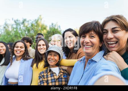Gruppe von Menschen aus mehreren Generationen, die Selfie mit der Telefonkamera machen - multirassische Freunde verschiedener Altersgruppen, die Spaß miteinander haben - Hauptfokus auf zwei Rechte Stockfoto