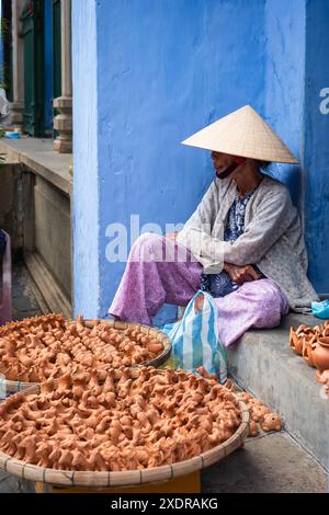 Vietnamesische alte Frau mit traditionellem konischem Hut in der Altstadt von Hoi an, Vietnam. Ältere Vietnamesen tragen einen traditionellen Sonnenhut, der auf der Straße verkauft Stockfoto