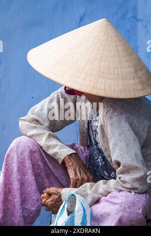 Vietnamesische alte Frau mit traditionellem konischem Hut in der Altstadt von Hoi an, Vietnam. Ältere Vietnamesen tragen einen traditionellen vietnamesischen Sonnenhut. Reisefoto Stockfoto