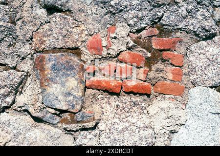 Textur der alten Hauswand aus Granitsteinen und roten Ziegeln. Stockfoto