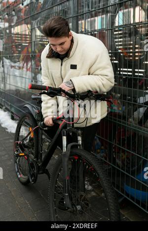 Ein junger Europäer, der in einer Winterjacke gekleidet ist, fährt mit dem Fahrrad Stockfoto