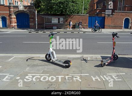 Zwei E-Scooter auf dem Straßenbelag, der für den Parkplatz von elektrischen Mietrollern markiert ist, in hammersmith, london, england Stockfoto