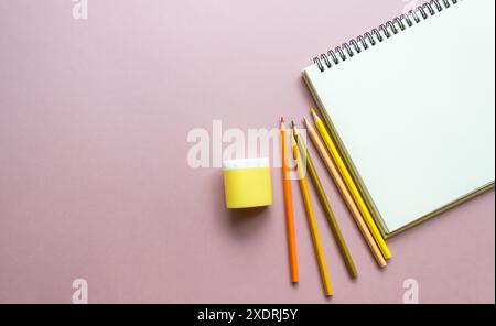 Helle Schulutensilien auf schlichtem Hintergrund. Bleistift, Spitzer, Notizbücher, Skizzenbuch. Back-to-School-Konzept, Künstlerkonzept Stockfoto