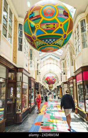 London, Großbritannien. Juni 2024. Die Burlington Arcade, die gehobene traditionelle Einkaufspassage im Londoner Mayfair, ist mit einem langen Teppichläufer im „Sporting Club“-Stil und riesigen Globus-Bälle dekoriert, in denen viele der Sportwettkämpfe des Sommers stattfinden, darunter Fußball, Olympische Sportarten und natürlich Tennis. Quelle: Imageplotter/Alamy Live News Stockfoto