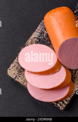 Gekochte vegane oder vegetarische Wurst aus Fleischersatz mit Salz und Gewürzen auf dunklem Betonhintergrund Stockfoto