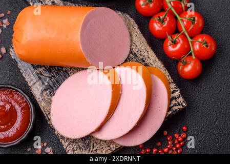 Gekochte vegane oder vegetarische Wurst aus Fleischersatz mit Salz und Gewürzen auf dunklem Betonhintergrund Stockfoto