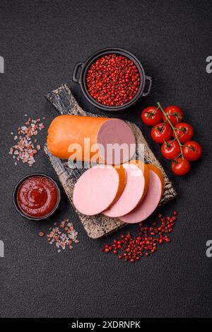 Gekochte vegane oder vegetarische Wurst aus Fleischersatz mit Salz und Gewürzen auf dunklem Betonhintergrund Stockfoto