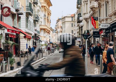 Nizza, Frankreich - 19. April 2024: Blick auf die Rue de France in Nizza mit einem unscharfen Motorradfahrer im Vordergrund Stockfoto