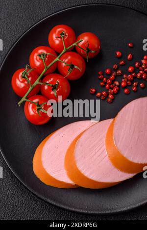 Gekochte vegane oder vegetarische Wurst aus Fleischersatz mit Salz und Gewürzen auf dunklem Betonhintergrund Stockfoto