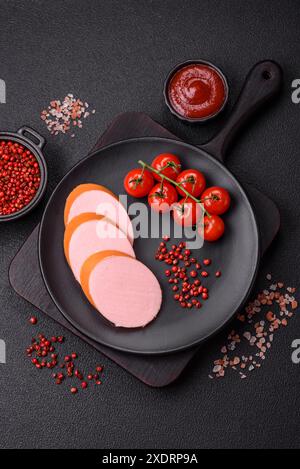 Gekochte vegane oder vegetarische Wurst aus Fleischersatz mit Salz und Gewürzen auf dunklem Betonhintergrund Stockfoto