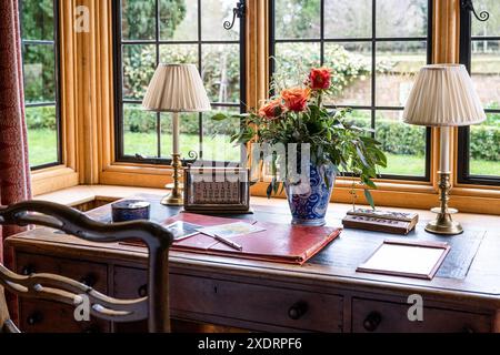 Zwei Schreibtischlampen und Rosen im Fenster der Bibliothekserweiterung. Tudor Farmhouse aus dem 16. Jahrhundert, Hertfordshire, England, Vereinigtes Königreich Stockfoto