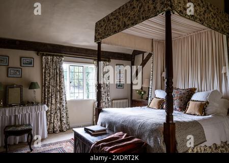 Georgianisches Himmelbett mit Chateaurenard-Stoff von Christopher Moore im 16. Jahrhundert Tudor Farmhouse, Hertfordshire, England, Großbritannien. Stockfoto