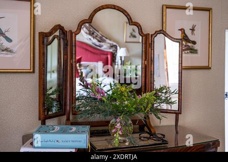 Schnittblumen und Bücher mit Vintage-Spiegel in Tudor Farmhouse aus dem 16. Jahrhundert, Hertfordshire, England, Großbritannien. Stockfoto