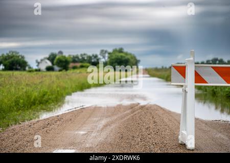 Selektiver Fokus auf den Schotter, der in Hochwasser mündet und die Straße in einem ländlichen Gebiet bedeckt Stockfoto