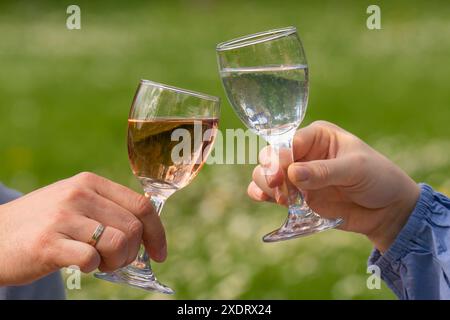 Männliche und weibliche Hände halten Glas Wein und Wasser. Das Paar verbringt Zeit miteinander. Liebe, Urlaub. Stockfoto