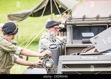 BROADCHALKE, WILTSHIRE, UK, 24. Juni 2024, Schuss von zwei Soldaten in Vintage-Kostümen, die sich auf einem Kriegsfahrzeug stützen, beim Chalke History Festival, dem führenden Geschichtsfestival Großbritanniens am Eröffnungstag, das Hunderttausende von Geschichtsbegeisterten anzieht (darunter Zehntausende von Schulkindern während des speziellen Schulfestivals an den ersten beiden Tagen). John Rose/Alamy Live News Stockfoto