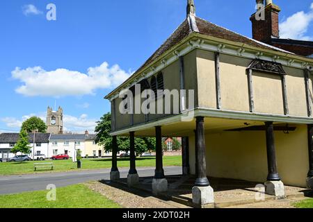 Das historische Market Cross House in New Buckenham mit dem Dorfgrün und dem Kirchturm dahinter, Norfolk, England, Großbritannien Stockfoto