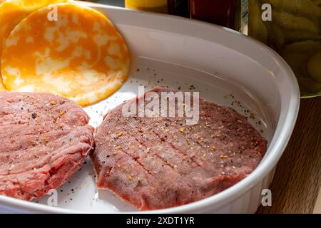 Zwei gefrorene Rindfleischburger mit Gewürzen und Cojakkäsescheiben. Grill wird vorgeheizt. Stockfoto