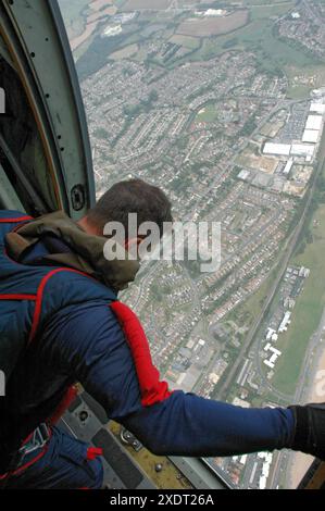 Ein Mitglied des RAF Falcons Fallschirmschirmschirmspringers schaut aus der seitlichen Tür des C130 Hercules-Flugzeugs, wenn sie Bexhill-on-Sea überqueren. Stockfoto