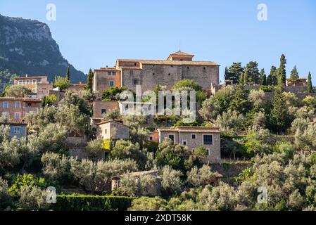 Atemberaubende Stadtlandschaft der kleinen Küstenort Deia auf Mallorca, Spanien. Traditionelle Häuser in Terrassen auf den Hügeln umgeben von grünen Bäumen entfernt Stockfoto