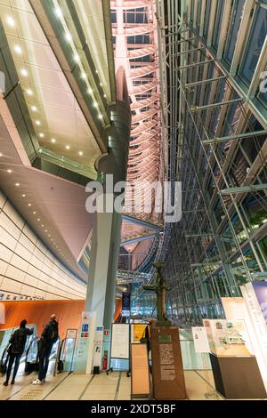 Vertikaler Weitwinkelblick entlang des Innenraums des Tokyo International Forums am Abend, zwei Personen vor der Eingangstreppe. Stockfoto