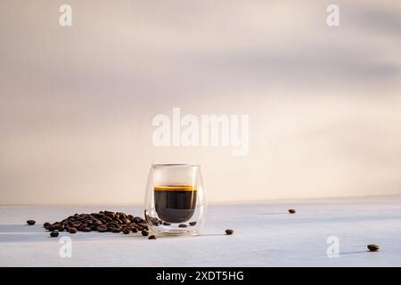 Eine Tasse Espresso mit Kaffeebohnen auf einer weißen Tischplatte am Morgen Stockfoto