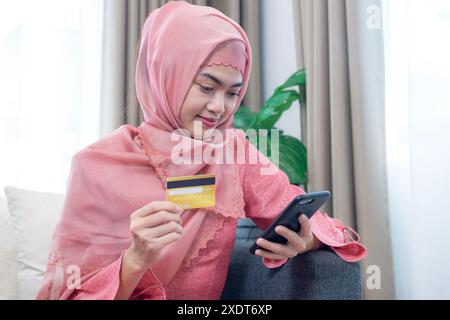 Eine junge muslimische Frau bezahlt gerne mit einer Kreditkarte für Online-Shopping Stockfoto