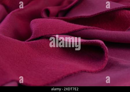 Ein Stück Stoff liegt in wunderschönen Wellen. Lagen aus französischem Frottee-rosa Amaranth-Textil. Schnitt zum Nähen, weiches Material, dichtes Gewebe, Gewebehintergrund Stockfoto