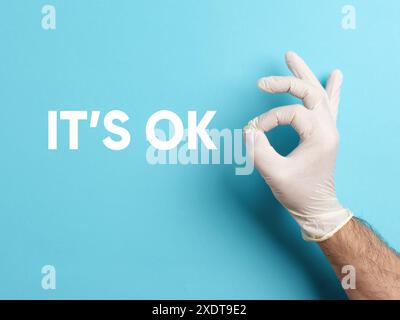 Männliche Hand trägt weißen medizinischen chirurgischen Handschuh, der OK Zeichen Geste macht. Mit dem Wort ist es OK. Stockfoto