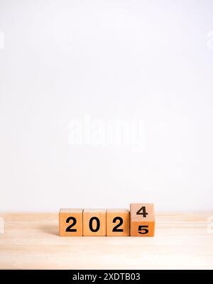 2025 ein frohes neues Jahr mit dem Wechsel zu Konzepten der neuen Ära. Umkehren von Kalendernummern von 2024 bis 2025 Jahren auf Holzwürfelblöcken isoliert auf Holztisch und weiß Stockfoto