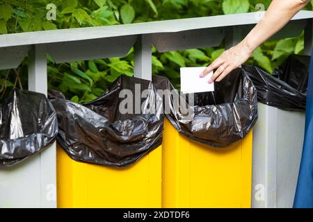Eine Frau mit einem Ring am Ringfinger wirft ein Stück Papier in den Müll Stockfoto
