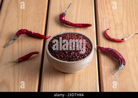 Rote Pfefferflocken. Rote Chilischoten in einer Holzschale auf Holztisch. Getrocknete Chilischoten Stockfoto