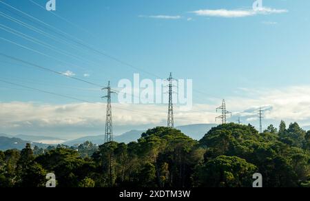 Landschaft mit Strommasten und Hochspannungsleitungen in Harmonie mit der Natur auf blauem Himmel Hintergrund. Stockfoto