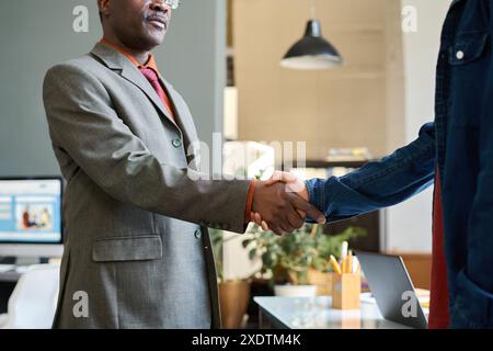 Zugeschnittene Aufnahme eines afroamerikanischen Geschäftsmannes, der nach erfolgreichem Geschäftstreffen im Büro die Hand mit einem Kollegen oder Partner schüttelt Stockfoto