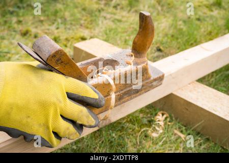 Horizontaler Hochwinkel-Studioaufnahme eines kleinen Vintage-Holzhobels. Altes Zimmermannswerkzeug mit Holzwürfellöchern darin. Dünne Holzspäne. Zimmerei c Stockfoto