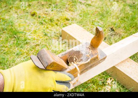 Horizontaler Hochwinkel-Studioaufnahme eines kleinen Vintage-Holzhobels. Altes Zimmermannswerkzeug mit Holzwürfellöchern darin. Dünne Holzspäne. Zimmerei c Stockfoto