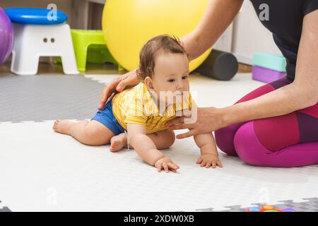 Der Physiotherapeut hilft einem Jungen, seine motorischen Fähigkeiten zu entwickeln Stockfoto