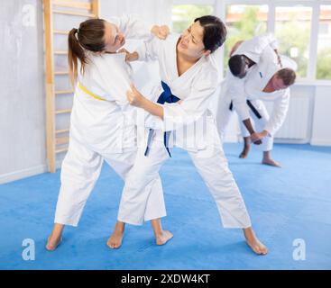 Mädchen, das eine Frau mit Jiu Jitsu anzapft, die sich im Fitnessstudio unterwirft Stockfoto