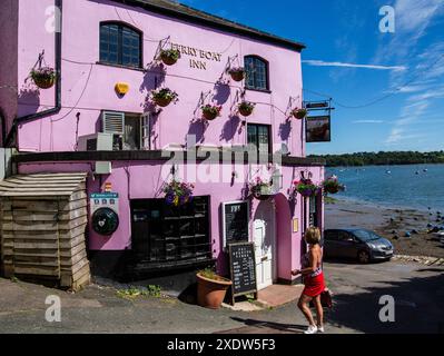 Person, die in einen lebhaften lila Pub geht, das Ferry Boat Inn Dittisham Devon UK nahe der Uferpromenade unter einem klaren blauen Himmel Stockfoto