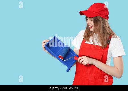 Malerin mit Malerwalze und Tablett auf blauem Hintergrund Stockfoto