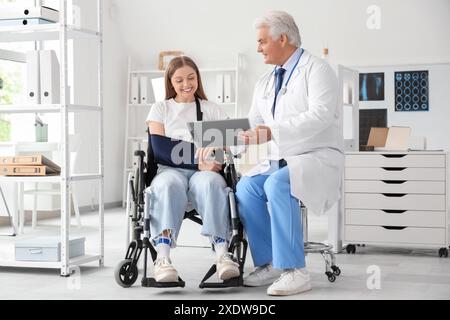Junge Frau im Rollstuhl mit gebrochenem Arm, Arztbesuch im Krankenhaus Stockfoto