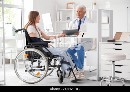 Junge Frau im Rollstuhl mit gebrochenem Arm, Arztbesuch im Krankenhaus Stockfoto