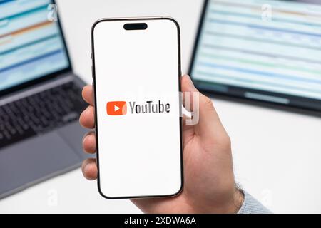 PRAG, TSCHECHISCHE REPUBLIK - 21. JANUAR 2024: YouTube-Logo auf dem Bildschirm des Smartphones in der Hand des Mannes auf dem Hintergrund des Arbeitsplatzes. Stockfoto