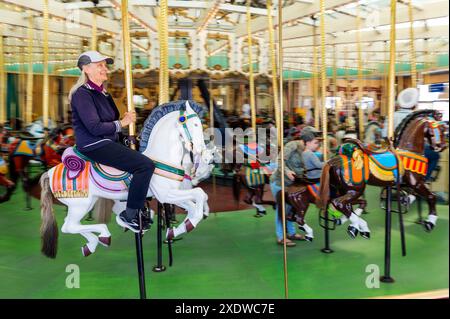 Einsame ältere Frau, die 1911 auf dem Looff Carousel reitet; National Historic Landmark; Santa Cruz Beach Boardwalk; Santa Cruz; Kalifornien; USA Stockfoto