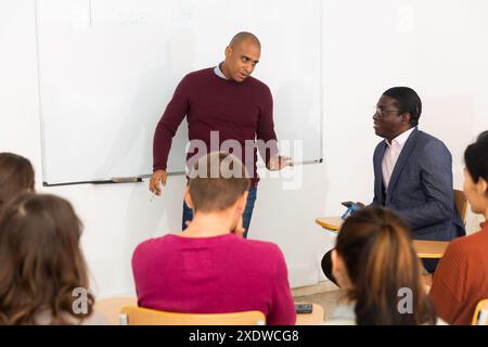 Der hispanische Dozent zeigt seinen Schülern etwas an Bord Stockfoto