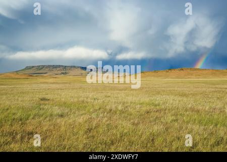 Square butte und ein Regenbogen in einem Sommersturm über der Prärie bei ulm, montana Stockfoto