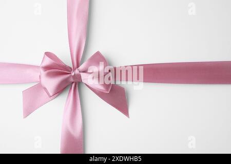 Pinkes Satinband mit Schleife auf weißem Hintergrund, Draufsicht Stockfoto
