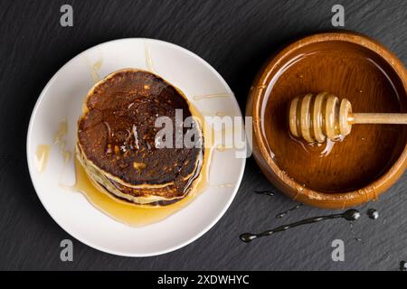 Köstliche frisch zubereitete Pfannkuchen mit Honig, süßer Bienenhonig auf Milchpfannkuchen Stockfoto