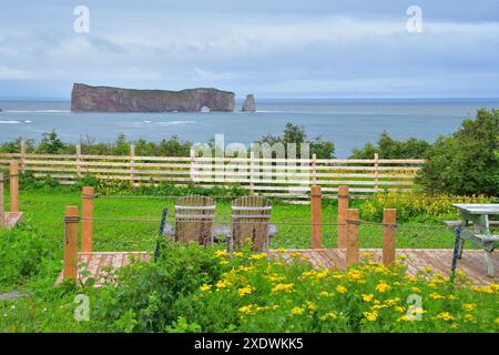 Adirondack-Stühle auf der Terrasse mit Blick auf den Percé-Felsen riesige schiere Felsformation im Golf von Saint Lawrence an der Spitze der Halbinsel Gaspé in Québ Stockfoto