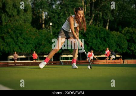 Hockeyspielerin spielt an einem sonnigen Tag Feldhockey, Hockeyspielerin schlägt den Ball mit einem Stock, Feldhockey-Konzept Stockfoto